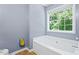 Bathroom featuring a white tub under a bright window with neutral-toned walls and tile floor at 3832 Augustine Pl, Rex, GA 30273