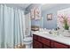 Bathroom featuring a shower with light blue shower curtain, cherry vanity, and floral artwork at 3832 Augustine Pl, Rex, GA 30273
