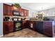 Well-lit kitchen featuring dark wood cabinets, black appliances, tile backsplash, and tile flooring at 3832 Augustine Pl, Rex, GA 30273