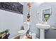 Stylish half bath featuring a pedestal sink, oval mirror, and contemporary decor at 3832 Augustine Pl, Rex, GA 30273