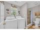Bathroom with a laundry area, a commode, and a beautifully tiled walk-in shower with a river rock floor at 2560 Fairlane Dr, Cumming, GA 30041
