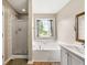Bright bathroom with tub and shower, featuring tile and a decorative mirror at 71 Barrington Dr, Hiram, GA 30141