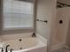 Bathroom featuring soaking tub, separate shower, and a large window for natural light at 1570 Jami Hollow Way, Lawrenceville, GA 30043