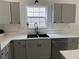 Close up view of a sink in the updated kitchen with gray cabinets and stone countertops at 1570 Jami Hollow Way, Lawrenceville, GA 30043