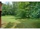 Expansive grassy backyard surrounded by tall trees, offering privacy and space at 174 Village Dr, Hiram, GA 30141
