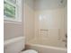 Bathroom with a shower-tub combo, toilet, standard tub faucet and shower head, and a bright window at 174 Village Dr, Hiram, GA 30141