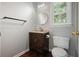 Small bathroom with a dark brown vanity, toilet, mirror, and a bright, window for natural light at 174 Village Dr, Hiram, GA 30141