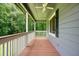 Cozy covered front porch featuring wood floors, white railings, and a ceiling fan with green trees in the background at 174 Village Dr, Hiram, GA 30141