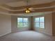 Spacious bedroom featuring a tray ceiling, ceiling fan, carpet flooring, and natural light from the many windows at 3457 Dacite Ct, South Fulton, GA 30349