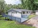 White brick home with a charming deck and black-trimmed windows nestled among mature trees at 8035 Rockbridge Rd, Lithonia, GA 30058