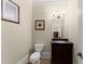 Well-lit powder room features a dark vanity with granite countertop, and decorative mirror at 1310 Settles Rd, Suwanee, GA 30024