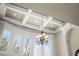 Close-up of an elegant coffered ceiling and an ornate chandelier above large windows, enhancing natural light at 1310 Settles Rd, Suwanee, GA 30024