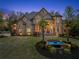 Elegant stone home with manicured lawn, water feature and palm trees at dusk at 1310 Settles Rd, Suwanee, GA 30024