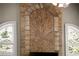 Close-up of a stone fireplace with a fan and arched windows at 1310 Settles Rd, Suwanee, GA 30024