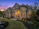 Stunning stone and brick home exterior featuring arched entryways, lush landscaping, and meticulously manicured lawn at 1310 Settles Rd, Suwanee, GA 30024