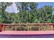 A red wooden deck overlooks a lush green forest in this peaceful outdoor setting at 4395 Wildbrooke Pkwy, Cumming, GA 30041