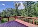 A red wooden deck overlooks a lush green forest in this peaceful outdoor setting at 4395 Wildbrooke Pkwy, Cumming, GA 30041
