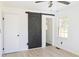 Bedroom featuring wood laminate flooring, natural light, and a black sliding barn door at 4011 Lake Carlton Rd, Loganville, GA 30052