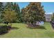 Spacious backyard with mature trees, large manicured lawn, and partial fence at 5176 Ashbury Manor Ln, Sugar Hill, GA 30518