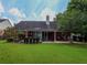 Lush backyard with patio, well-manicured lawn, brick exterior, and mature trees at 5176 Ashbury Manor Ln, Sugar Hill, GA 30518