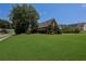 Expansive front yard of the red brick home, showcasing mature landscaping and a spacious green lawn at 5176 Ashbury Manor Ln, Sugar Hill, GA 30518