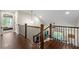 Hallway with hardwood floors, leading to stairs with dark wood and wrought iron bannister overlooking the living room at 5015 Monticello Dr, Villa Rica, GA 30180
