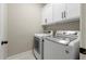 Bright laundry room featuring white washer and dryer units with updated cabinets and stylish hardware at 5015 Monticello Dr, Villa Rica, GA 30180
