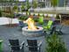 Outdoor stone fire pit with Adirondack chairs in a pea gravel seating area in a green community setting at 3450 Commander Cv, Suwanee, GA 30024