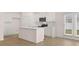 Bright, all-white kitchen featuring a center island, stainless steel appliances, and a view to the backyard at 205 Silver Moon Dr, Loganville, GA 30052