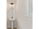 Compact powder room featuring a pedestal sink, round mirror, and modern lighting at 1995 Deco Dr, Kennesaw, GA 30144