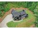 Aerial view of a dark modern farmhouse boasting a basketball court, lush lawn and wooded surroundings at 2100 Mountain Cove Ct, Woodstock, GA 30188
