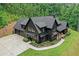 Aerial view of a modern farmhouse boasting a three car garage, basketball court, lush lawn and woods at 2100 Mountain Cove Ct, Woodstock, GA 30188