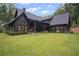 Stunning backyard with a covered patio, lush lawn, mature trees, and stylish black exterior at 2100 Mountain Cove Ct, Woodstock, GA 30188