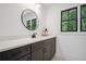 Modern bathroom features dark vanity, round mirror, and a window with wooded view at 2100 Mountain Cove Ct, Woodstock, GA 30188