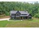Stunning dark modern farmhouse with inviting front porch and lush lawn with a beautiful wooded backdrop at 2100 Mountain Cove Ct, Woodstock, GA 30188