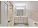 Well-lit bathroom featuring a white vanity, patterned wallpaper, and a shower in the adjacent room at 6339 Cornelia Dr, Douglasville, GA 30134
