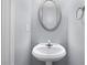 Powder room with a pedestal sink and decorative oval mirror at 173 Oakland Hills Way, Lawrenceville, GA 30044