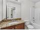 Bathroom with granite counters, brown cabinets, tub, and tile flooring at 173 Oakland Hills Way, Lawrenceville, GA 30044