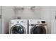 Bright laundry room with white washer and dryer, shelf and neutral paint at 173 Oakland Hills Way, Lawrenceville, GA 30044
