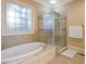 Luxurious bathroom featuring a jacuzzi bathtub, glass shower, and tiled walls beneath a decorative window at 1255 Mcminn Way, Snellville, GA 30078