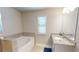 Bright bathroom featuring a soaking tub, walk-in shower, and vanity with granite countertop and a window at 339 Cherryhill Ln, Woodstock, GA 30188