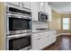 Stainless steel kitchen appliances featuring double oven, microwave, white cabinets, and granite countertops at 108 Donovan Ave, Locust Grove, GA 30248