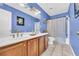 Bathroom with dual sinks, wood cabinets, blue walls, and bathtub at 4055 Inman Park Ln, Buford, GA 30519