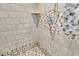 Close-up of tiled shower with decorative accents and pebbled floor at 4055 Inman Park Ln, Buford, GA 30519