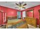 Bedroom with red walls, wood furniture, ceiling fan, and natural light at 4055 Inman Park Ln, Buford, GA 30519