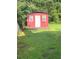 Backyard shot of a red shed with a white door and overgrown grass at 3155 E East Point E St, East Point, GA 30344