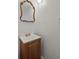A cozy bathroom with a wood vanity, white sink, and decorative mirror at 5861 Community Rd, Mableton, GA 30126