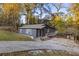 View of a charming home with a sloped driveway and a welcoming front porch, nestled in a wooded area at 5861 Community Rd, Mableton, GA 30126