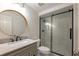 Modern bathroom boasts a sleek vanity, round mirror, and glass-enclosed shower with black trim at 10650 Centennial Dr, Alpharetta, GA 30022