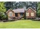 Charming brick home with manicured lawn, mature trees, and yellow shutters at 2525 Fairview Dr, Cumming, GA 30041